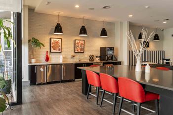 A modern kitchen with red chairs and a wooden floor.